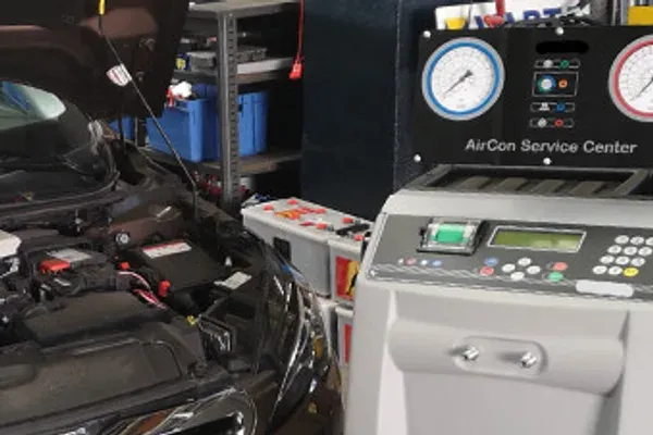 Station de charge de climatisation raccordée au compartiment moteur d'un véhicule