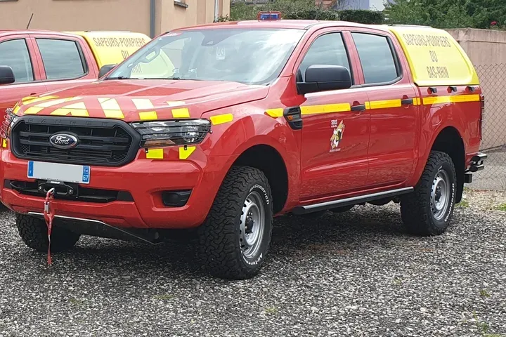 Pick-up 4x4 rouge de sapeurs-pompiers équipé de feux à éclats et de bandes réfléchissantes