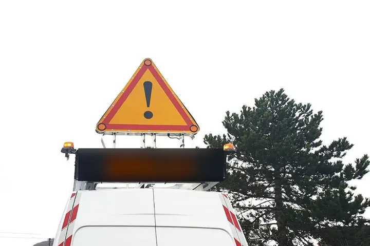 Fourgon de voirie surmonté d'un panneau à messages variables et d'un triangle de signalisation